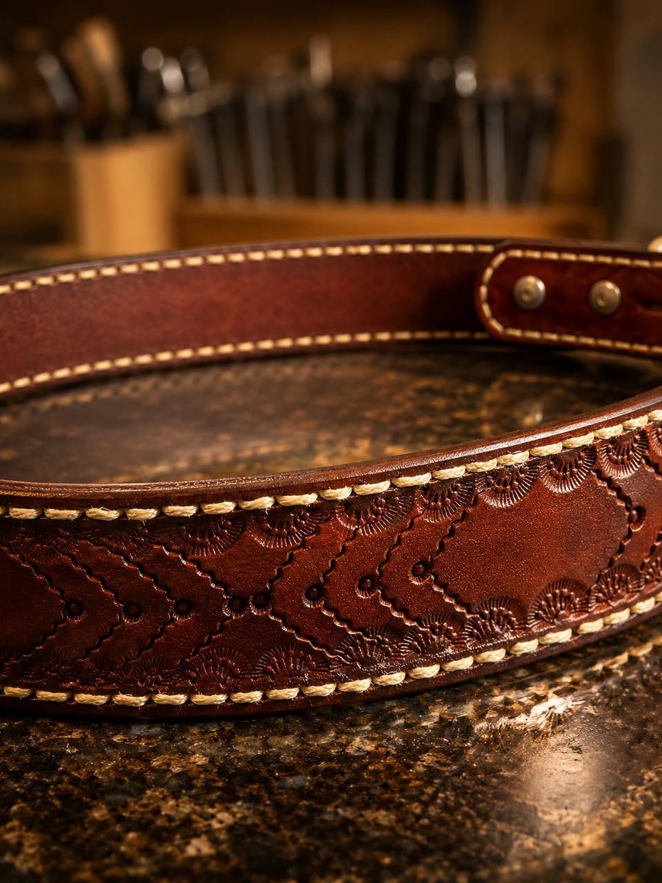 Brown laced tooled leather belt on a workbench.