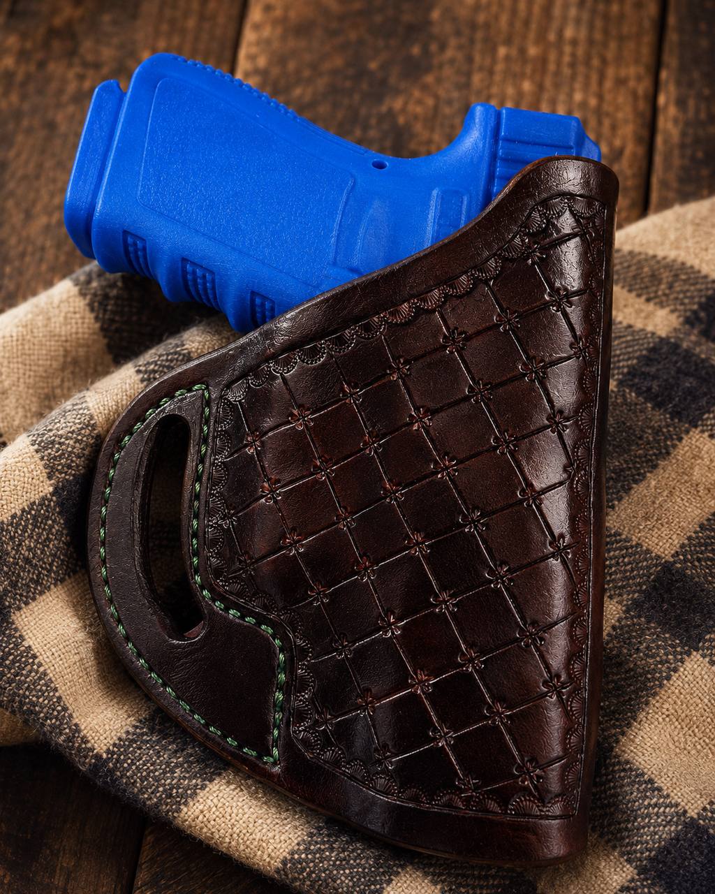 Dark tooled leather holster with green stitching.