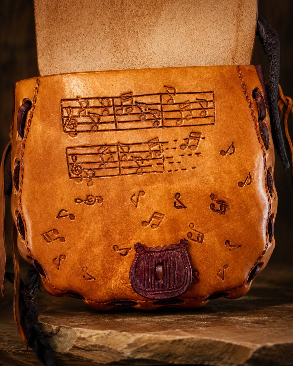 Open view of a harp tooled leather satchel with music notes.