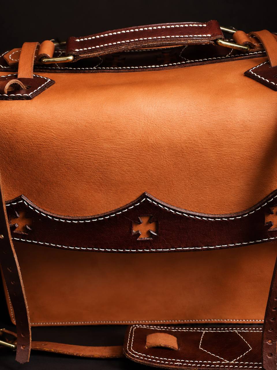 Close-up detail of a tan western leather satchel.