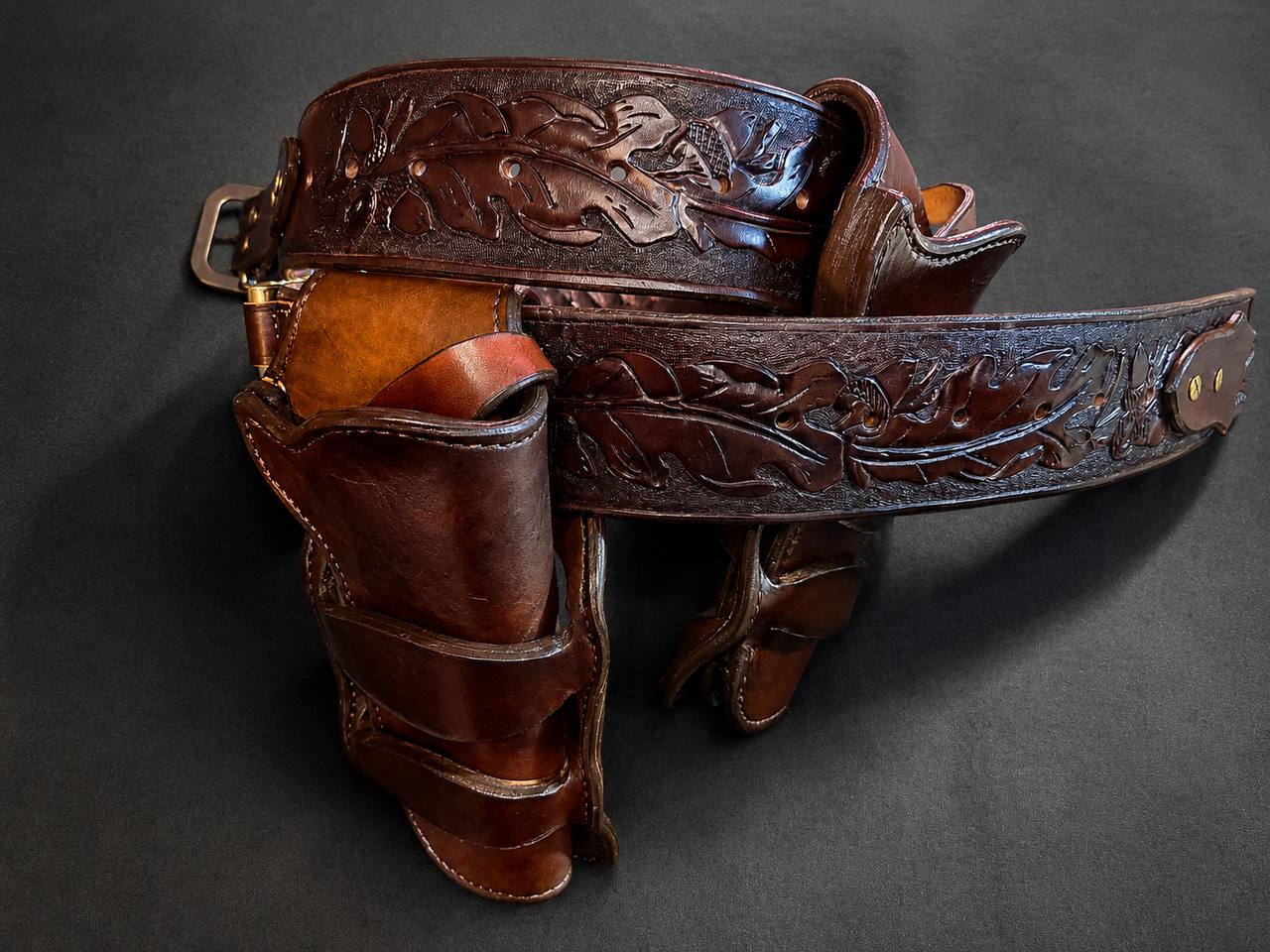 Tooled leather holster rig with carved leaf pattern.