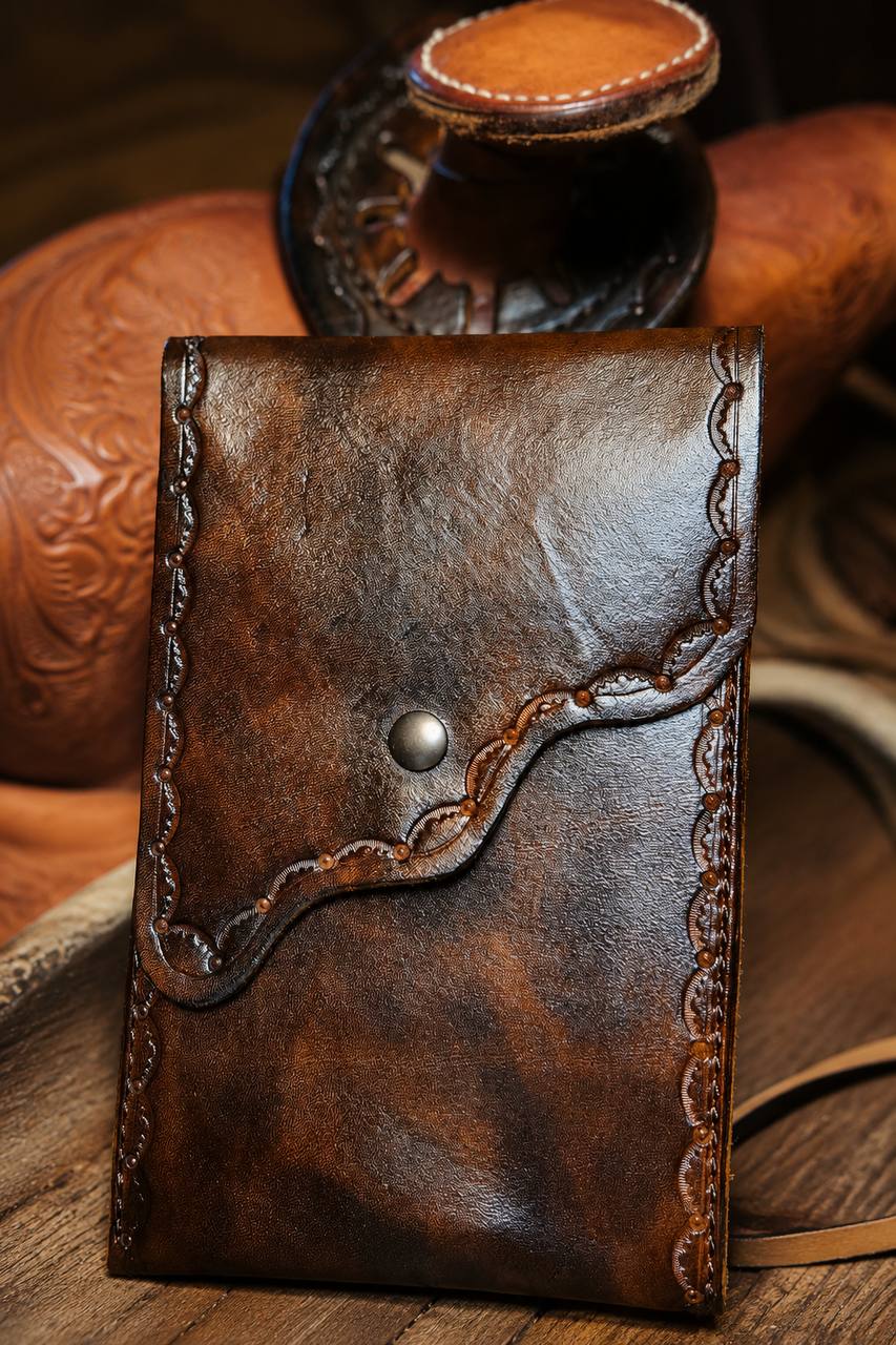 Tooled brown leather pouch with snap closure.