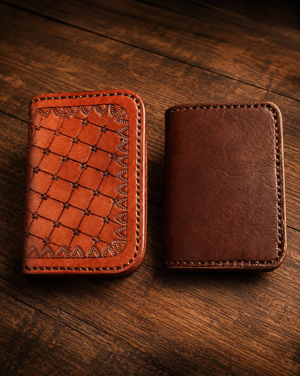 Pair of brown leather wallets, one with tooled detail.